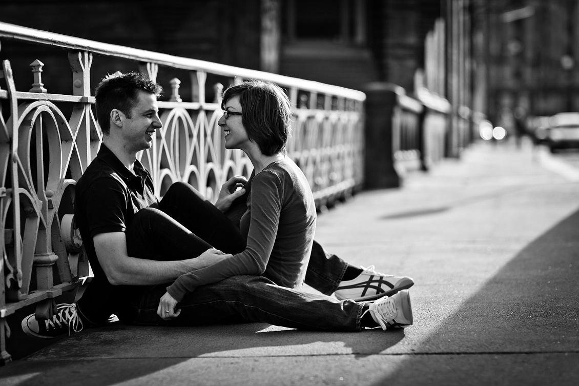 Engagement_shooting_hafencity_Hamburg_das_Paar_sitzt_auf_der_Brücke_und_lächelt_einander_an